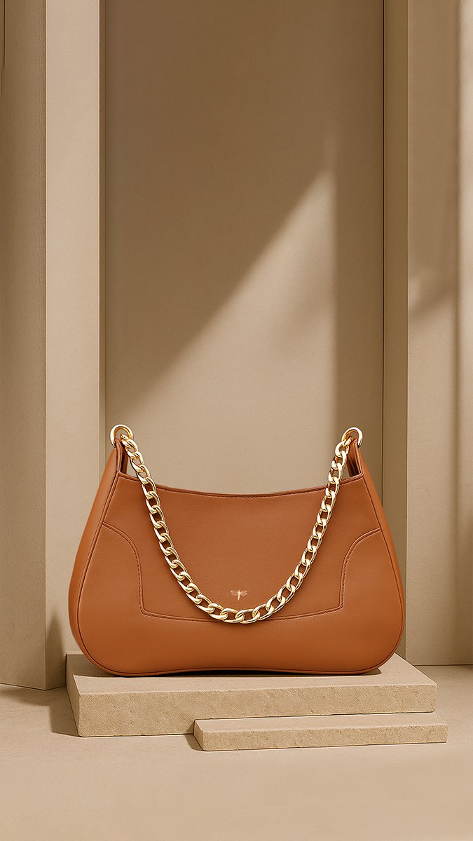 Bandolera camel con cadena dorada sobre un pedestal